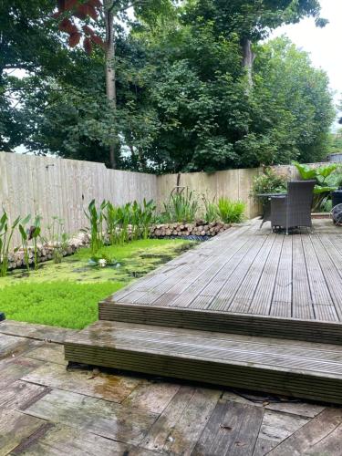 a wooden deck with a bench in a backyard at Parkside Lodge - Luxury Coastal Hideaway for Two in Brixham
