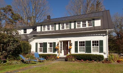 a white house with two chairs in the yard at Artful Lodging & Retreats in Montpelier