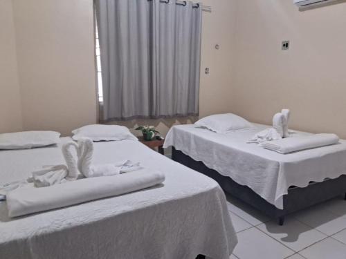 two beds in a room with white sheets at CASA PÔR DO SOl in Alter do Chao