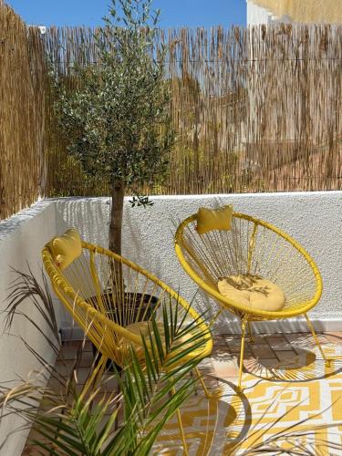 two yellow chairs and a tree on a patio at Gites du réservoir in Mauguio