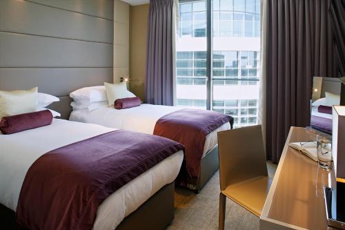 a hotel room with two beds and a window at Cheval Three Quays at The Tower of London in London