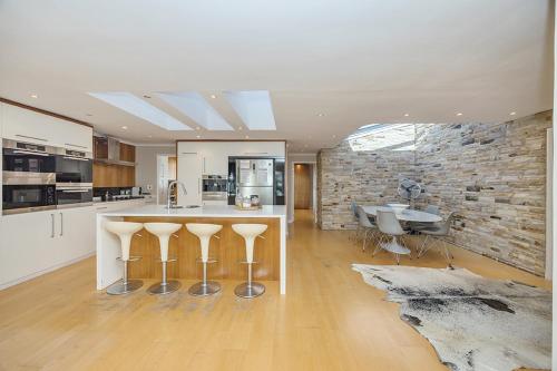 a kitchen with a bar with stools and a stone wall at The Island Beach Villa in Cape Town