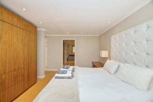 a bedroom with a large white bed with a large headboard at The Island Beach Villa in Cape Town
