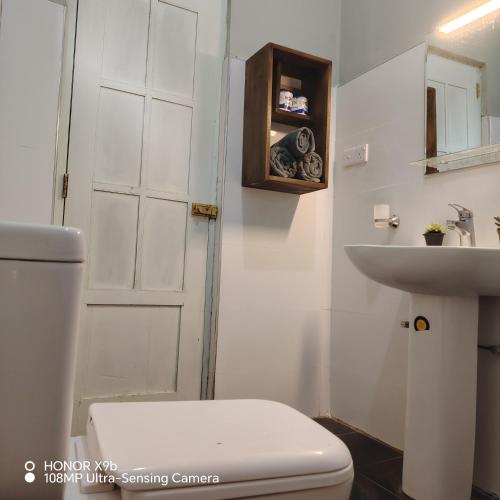 a white bathroom with a toilet and a sink at Ella Ceylonka in Ella
