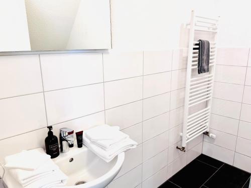 a white bathroom with a sink and a mirror at Inselsünn Hotel und Apartments in Spiekeroog
