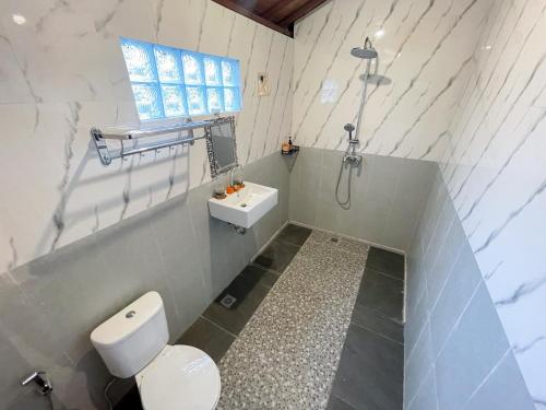 a white bathroom with a toilet and a sink at Pondok BIMA in Tegalalang