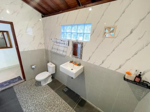a bathroom with a toilet and a sink and a window at Pondok BIMA in Tegalalang