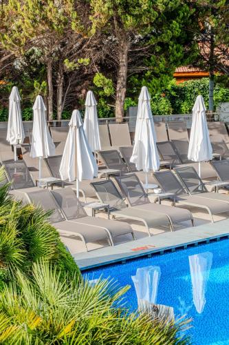 a group of lawn chairs with white umbrellas next to a pool at Flora Garden Ephesus Kusadasi - All Inclusive in Davutlar