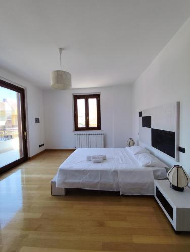 a white bedroom with a large bed and a window at Casa vacanze Brezza del Mar in Alghero