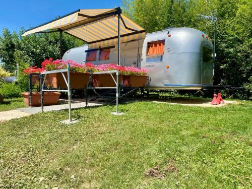 une caravane avec un toit et des fleurs dans une cour dans l'établissement Le Clos de Tanvol - Parking privé GRATUIT- Terrasse Privée - Climatisation - Caravane Airstream, à Viriat