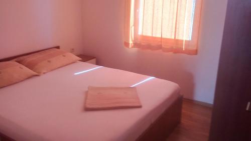 a small bedroom with a white bed with a wooden floor at Apartmani Trputec, otok Vir in Vir