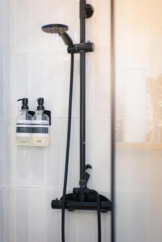 a stand up shower in a bathroom with two bottles at Gites du réservoir in Mauguio
