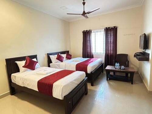 a hotel room with two beds and a tv at Harish Beach Resort in Rāmeswaram