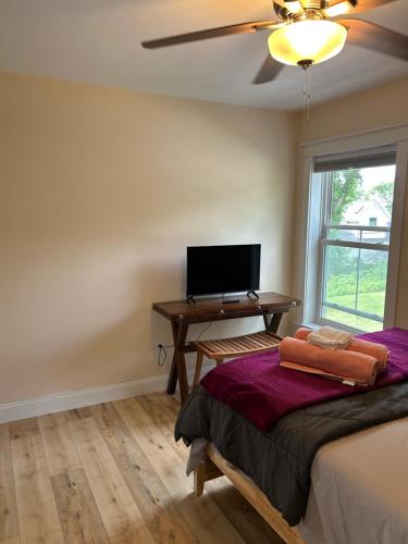a bedroom with a bed and a desk with a television at Roberts Lake House Room# 2 in Colchester