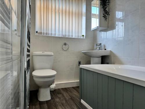 a bathroom with a toilet and a sink and a tub at Ash Cottage in Tollerton