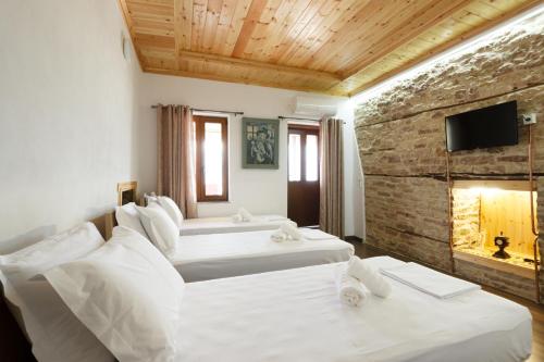 two white beds in a room with a fireplace at Rest & View Guesthouse in Gjirokastër