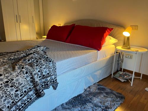 a bedroom with a bed with red pillows and a lamp at Terrazza Elce - A stone's throw from the Center in Perugia