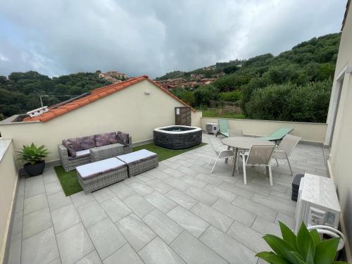a patio with a table and a couch and a table and chairs at Villino con terrazzo panoramico in Finale Ligure