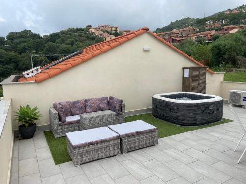 a patio with a hot tub and wicker furniture at Villino con terrazzo panoramico in Finale Ligure