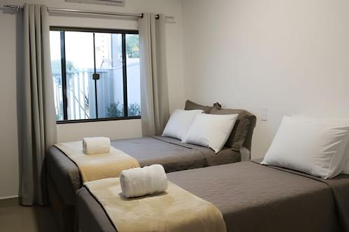 a small room with two beds and a window at Linda Casa com 2quartos para 5 pessoas in Foz do Iguaçu