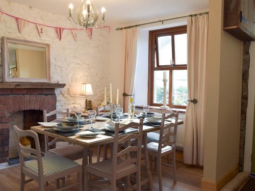 a dining room with a table and chairs and a fireplace at Moss Cottage in Burry Port