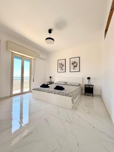 een witte slaapkamer met een bed en een groot raam bij La casa delle parole 2 in Agrigento