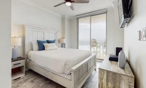 a white bedroom with a bed and a balcony at Gulf-Front Waterscape B401 Sundrenched in Fort Walton Beach