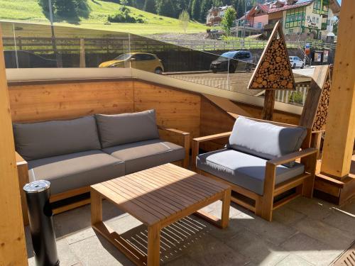 a balcony with a couch and a chair and a table at Fedaia Joy B&B in Canazei