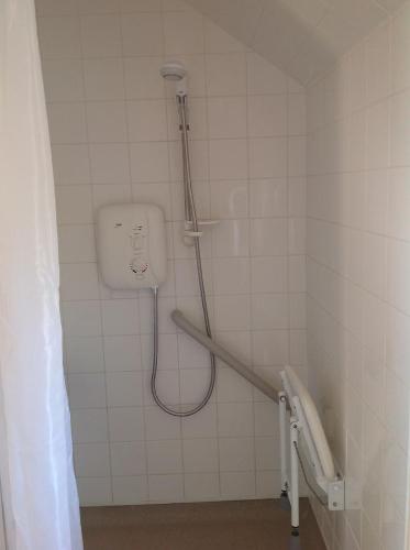 a bathroom with a shower in a tiled wall at Stable Cottages in Cowes