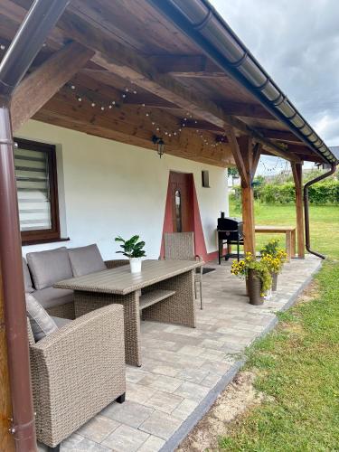 a patio with a table and chairs under a pergola at Urocze Roztocze Jacnia - domek 1 in Jacnia