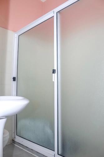 a glass shower door in a bathroom with a sink at Hotel Pousada Venus in São Filipe