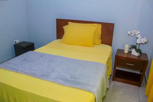 a bedroom with a bed with yellow sheets and a yellow pillow at Hotel Pousada Venus in São Filipe