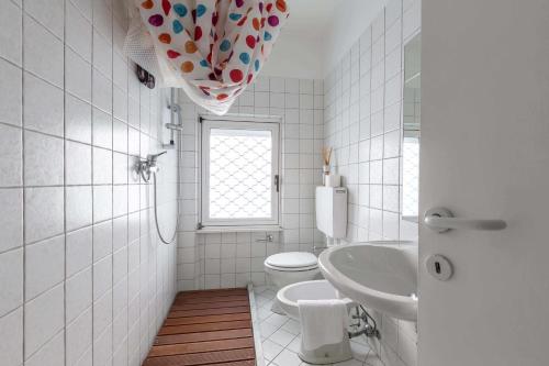 a white bathroom with a toilet and a sink at Torbole Holiday House in Nago-Torbole