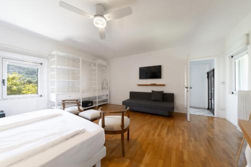 a white bedroom with a bed and a couch at Torbole Holiday House in Nago-Torbole