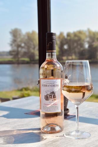 a bottle of white wine next to a wine glass at Het Maashotel in Broekhuizen