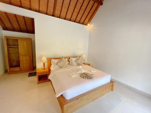 a bedroom with a large bed with white sheets at Pondok BIMA in Tegalalang