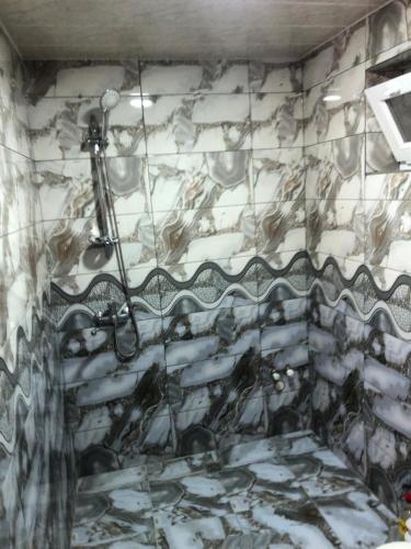 a shower in a bathroom with a marble wall at Kirayə ev in Mekhrably