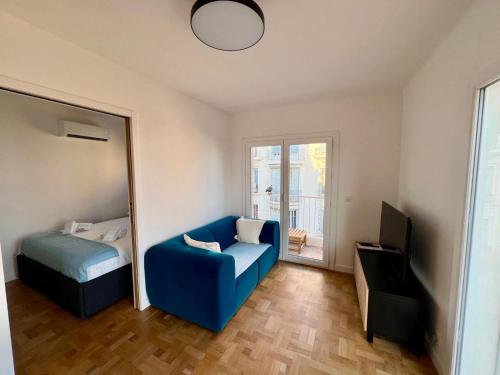 - une chambre avec un canapé bleu, un lit et un miroir dans l'établissement Appartement Vue Mer T2 Cosy, Plage à pied 3 mins, Coucher de Soleil, Parc privé, à Nice