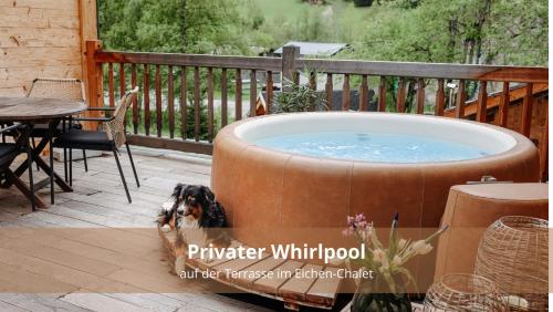 a dog sitting next to a hot tub on a deck at Chalet WaldHäusl luxuriöse Ferienwohnungen mit Sauna & Whirlpool, Kamin, Balkon oder Terrasse mit Bergblick in Heiligenblut