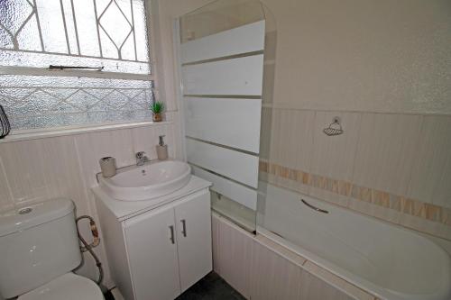 a bathroom with a sink and a toilet and a tub at Comfortable 4 Bedroom Flat in Germiston with WI-FI in Germiston