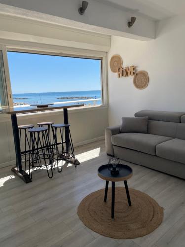 - un salon avec un canapé, une table et une grande fenêtre dans l'établissement Superbe appartement vue sur mer, à Valras-Plage