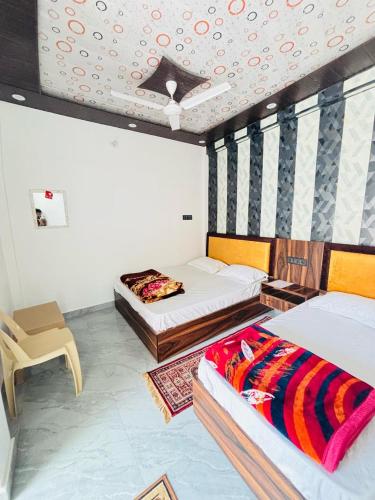 a room with two beds and a chair in it at Kanak Bihari Yatri Niwas, 100 Meter Ram Ki Paidi, Saryu River in Ayodhya