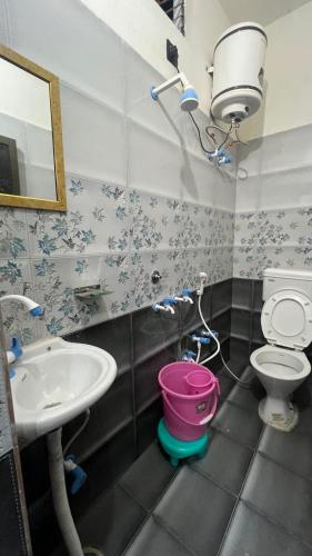 a bathroom with a sink and a toilet and a bucket at Kanak Bihari Yatri Niwas, 100 Meter Ram Ki Paidi, Saryu River in Ayodhya