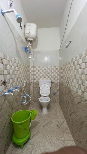a bathroom with a toilet and a green bucket at Kanak Bihari Yatri Niwas, 100 Meter Ram Ki Paidi, Saryu River in Ayodhya