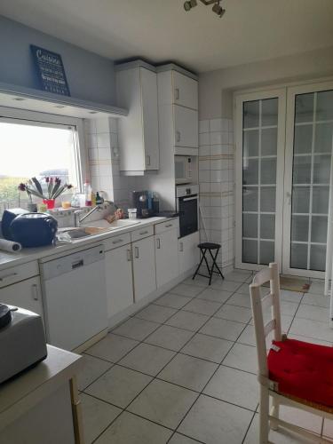 a kitchen with white cabinets and a sink and a window at Maison familiale, front mer in Lanildut