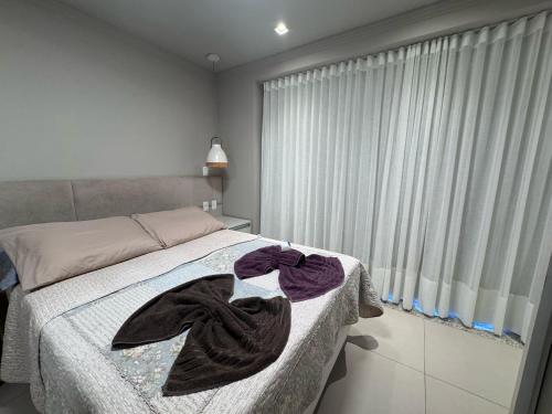 una camera da letto con un letto con due asciugamani sopra di Apartamento com Piscina no Centro e a poucos metros do mar de Torres -RS a Torres