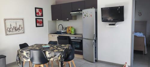 eine Küche mit Tisch, Kühlschrank und Fernseher in der Unterkunft locfarefarani in Sorède
