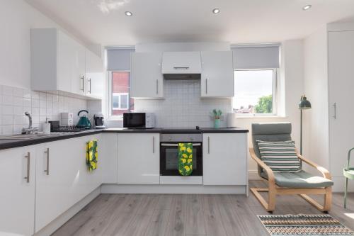 a kitchen with white cabinets and a chair in a room at Lytham St Annes Luxury Apartment - No 1 Tides Reach in Lytham St Annes