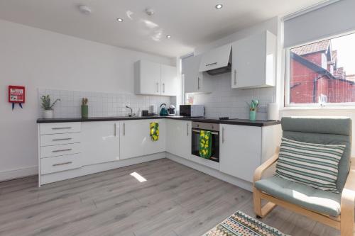 a kitchen with white cabinets and a chair and a window at Lytham St Annes Luxury Apartment - No 1 Tides Reach in Lytham St Annes