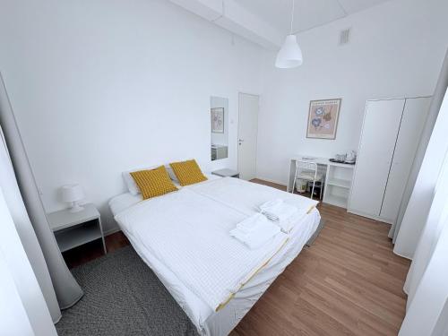 a white bedroom with a large white bed with yellow pillows at Endla Hostel ja Apartamendid in Haapsalu